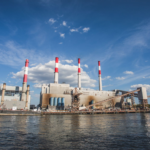 A wide view of Ravenswood Generating Station with chimneys and waterfront in New York City.
