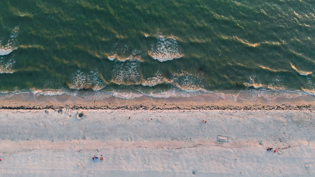 A stunning aerial view of Sarasota Beach, Florida featuring sandy shores and gentle waves at sunset.