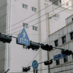 City street showcasing traffic lights and pedestrian signs in an urban setting with high-rise buildings.