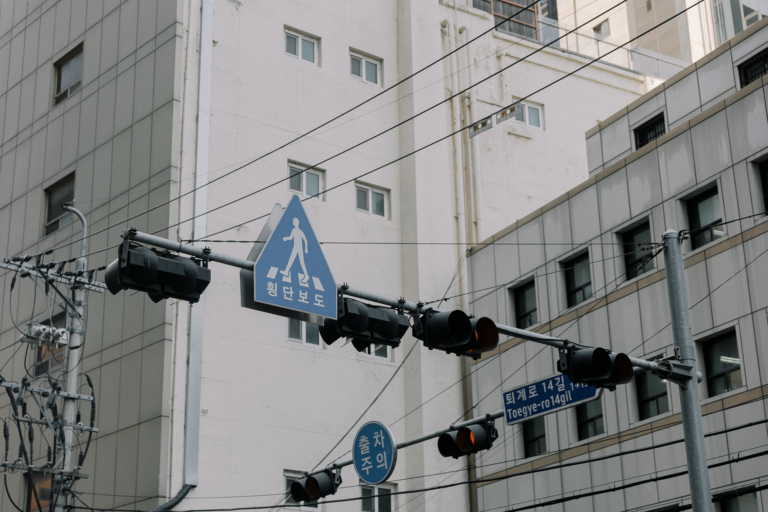 City street showcasing traffic lights and pedestrian signs in an urban setting with high-rise buildings.