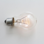A close-up of an illuminated incandescent light bulb against a white background.