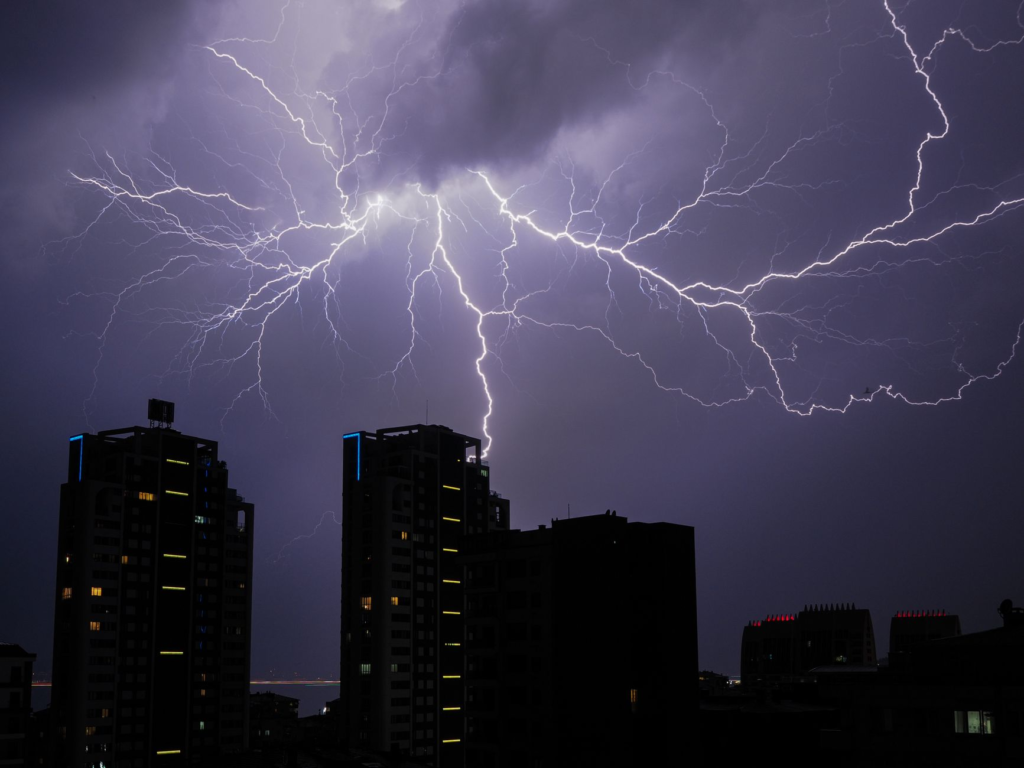 Stunning view of lightning bolts illuminating a cityscape at night, creating a dramatic and powerful scene.