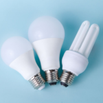 Three assorted LED and CFL light bulbs against a light blue background.