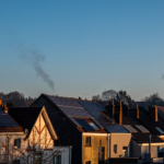 A row of houses displaying solar panels on their rooftops, reflecting sustainable energy practices.