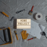 Flat lay of home improvement tools, paint samples, and blueprints for a DIY project.