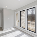 Spacious and bright room with large glass windows overlooking a serene outdoor setting.