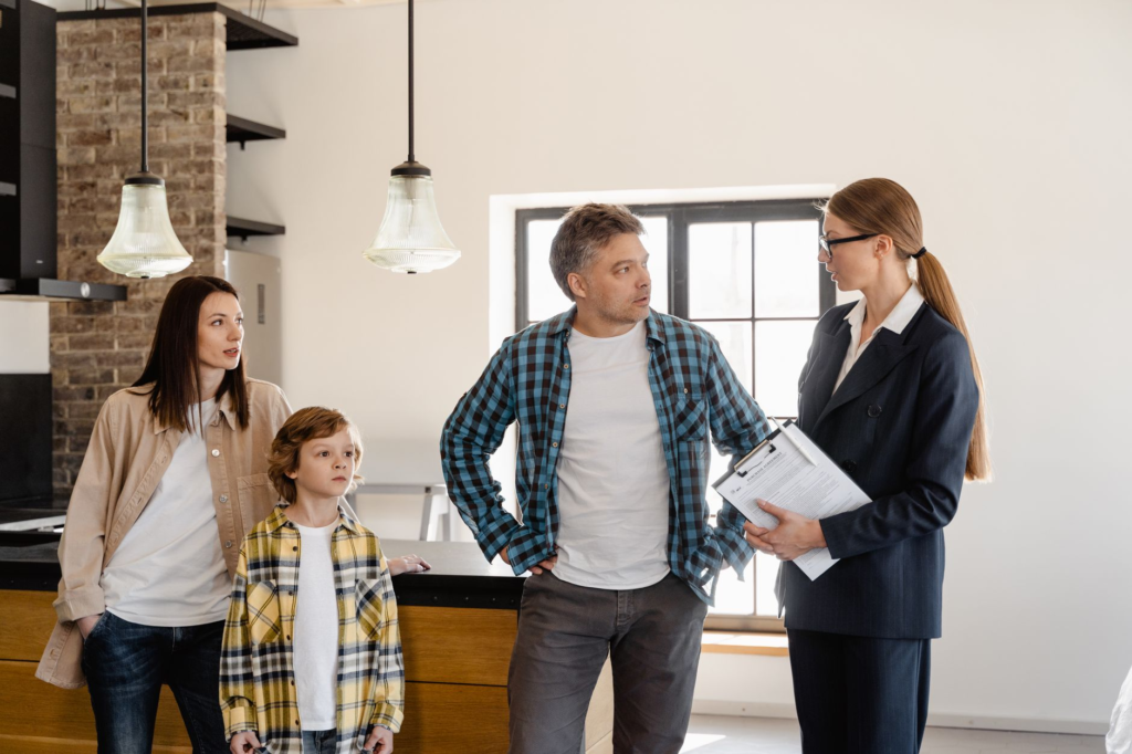 Family with child talks to real estate agent in modern kitchen during home showing.