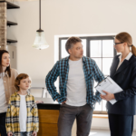 Family with child talks to real estate agent in modern kitchen during home showing.
