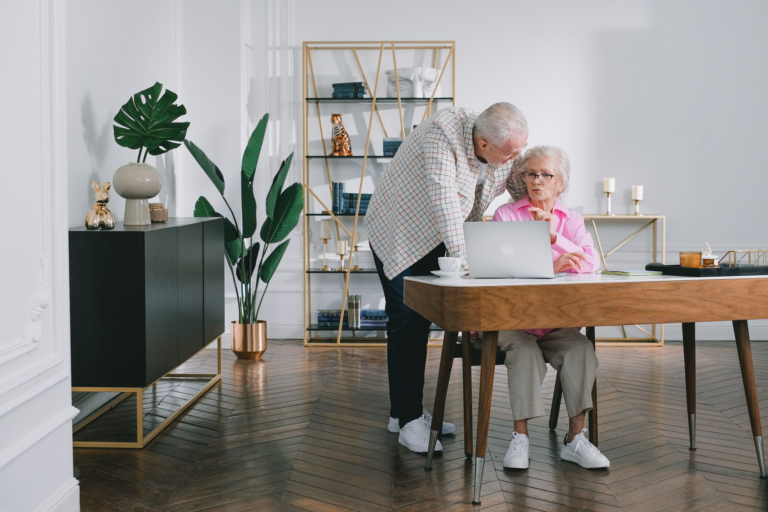 Senior couple using a laptop while discussing something in their modern living room.