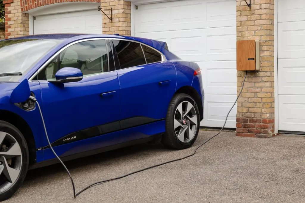 Blue electric car charging from a wall-mounted home charger